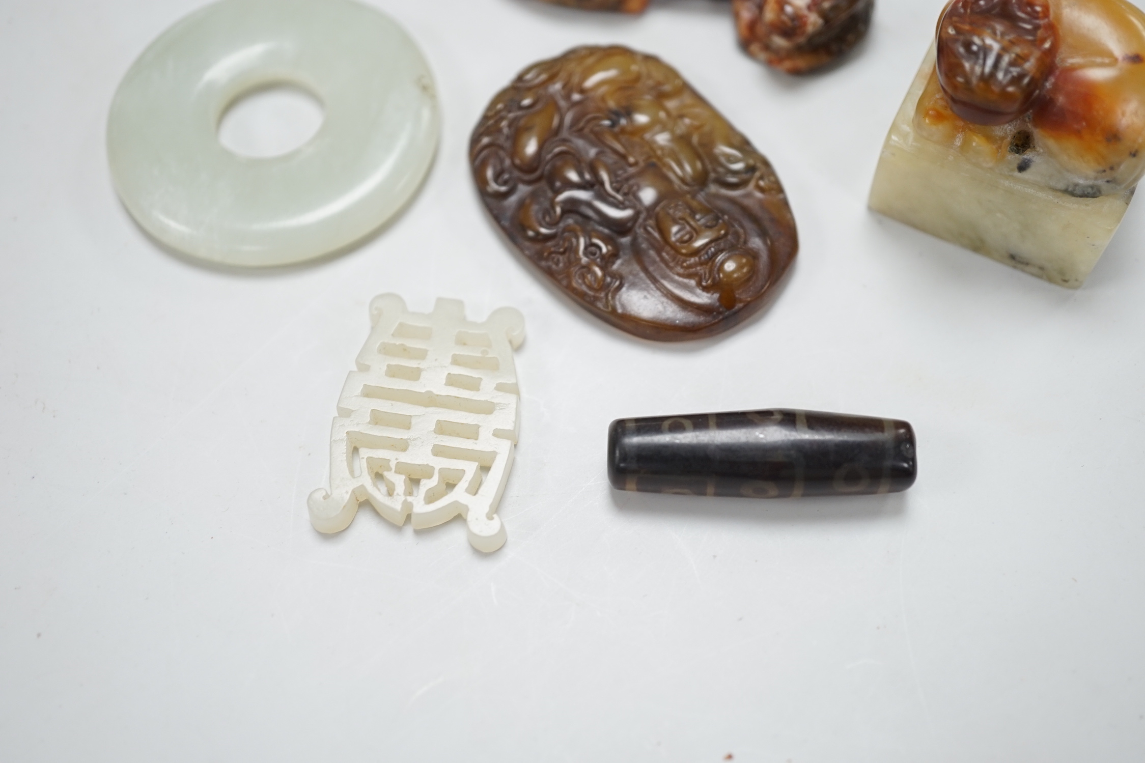 A Chinese pale celadon jade bi disc, a jade carving of the character ‘Shou’ , two hardstone carvings of creatures, an agate pendant of Guanyin in Tang dynasty style and a stained glass , bead in Tibetan style (6), disc 4
